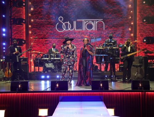 A vibrant live band performs on a colorful stage with dynamic lighting.