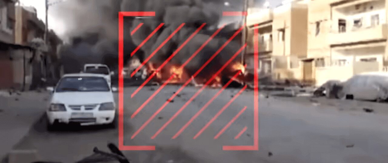 A scene of a fire burning on a street with smoke rising.